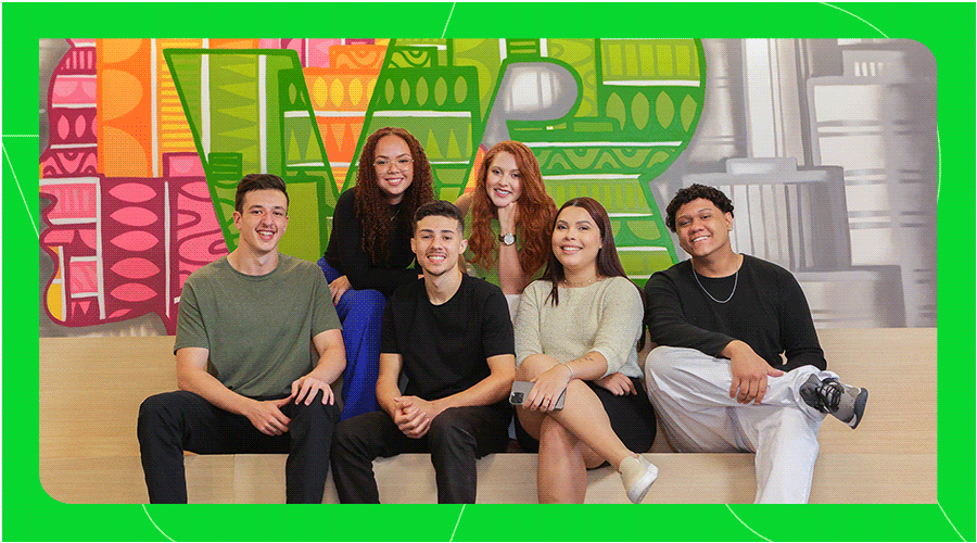 Imagem com um grupo de pessoas sorrindo, na frente de um letreiro da VR.